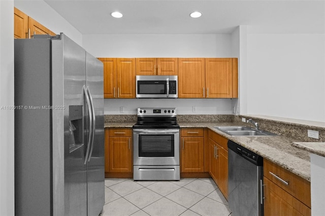 8206 SW 29th St Unit 104, Miramar, FL 33025 - kitchen featuring appliances with stainless steel finishes, a sink, brown cabinets, light tile patterned floors, and dark stone counters