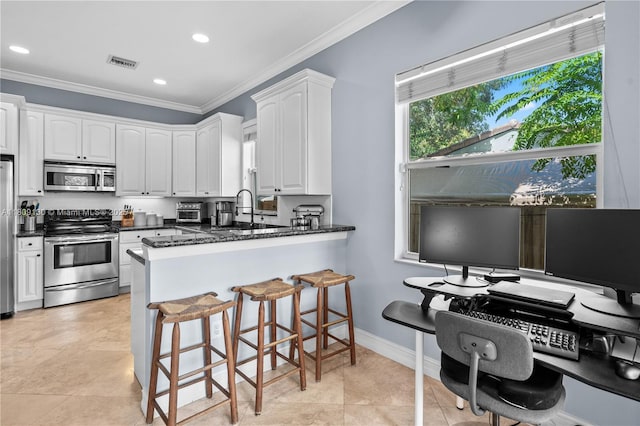 849 SW 11th Ct, Fort Lauderdale, FL 33315 - kitchen featuring stainless steel appliances, ornamental molding, white cabinets, a sink, and a kitchen breakfast bar
