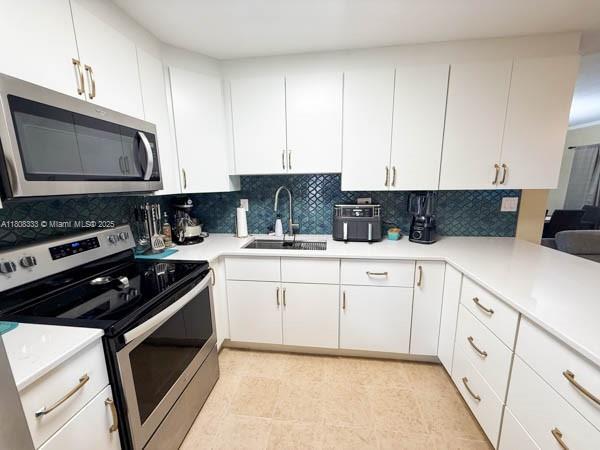 11321 SW 162nd Ter, Miami, FL 33157 - kitchen with stainless steel appliances, a sink, decorative backsplash, and white cabinets