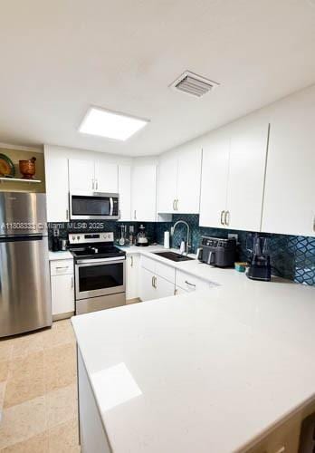11321 SW 162nd Ter, Miami, FL 33157 - kitchen featuring appliances with stainless steel finishes, a sink, backsplash, a peninsula, and light countertops