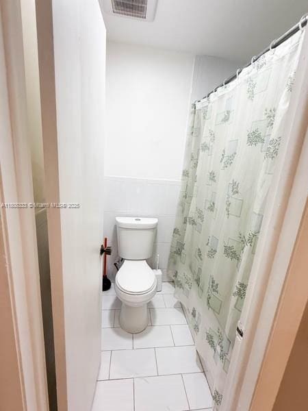 11321 SW 162nd Ter, Miami, FL 33157 - bathroom with toilet, tile patterned floors, tile walls, a wainscoted wall, and curtained shower