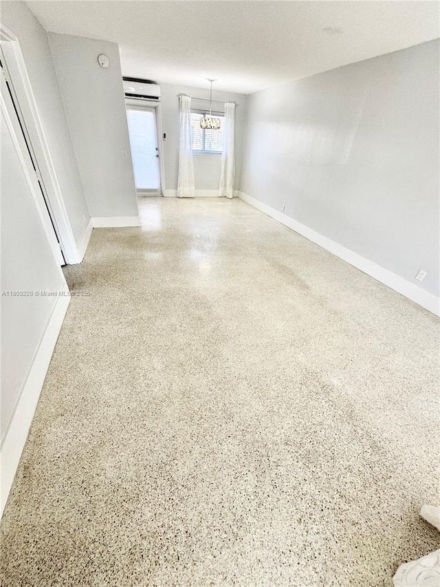 1601 SE 15th St Unit 1B, Fort Lauderdale, FL 33316 - empty room with speckled floor, a wall mounted AC, baseboards, and a chandelier