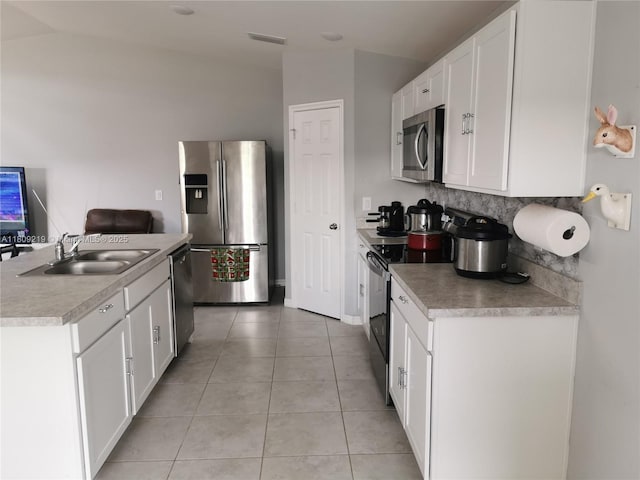 2116 5th Pl, Cape Coral, FL 33909 - kitchen featuring appliances with stainless steel finishes, a sink, white cabinetry, lofted ceiling, and light tile patterned flooring