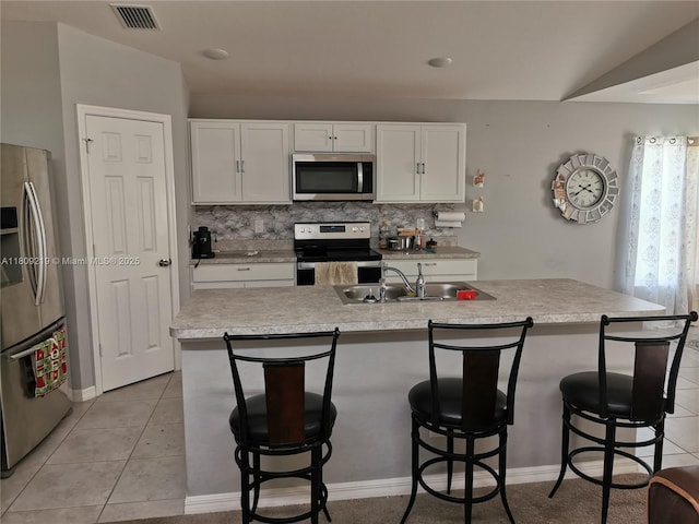 2116 5th Pl, Cape Coral, FL 33909 - kitchen featuring appliances with stainless steel finishes, a sink, white cabinetry, and a kitchen breakfast bar