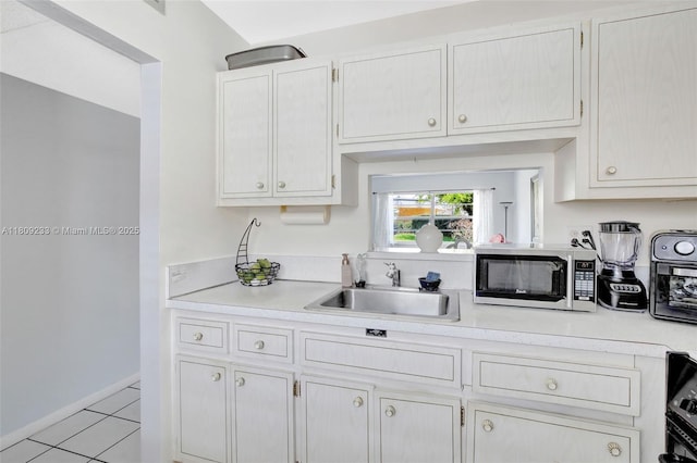 4441 NW 16th St Unit J108, Lauderhill, FL 33313 - kitchen featuring a sink, light countertops, light tile patterned flooring, white cabinets, and baseboards