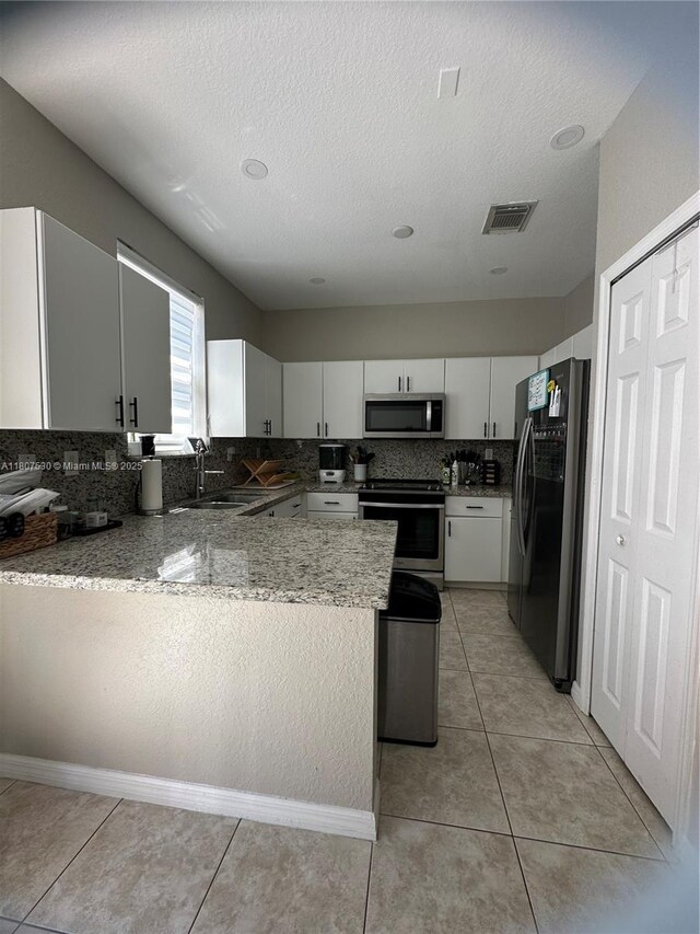 11921 SW 153rd Pl, Miami, FL 33196 - kitchen featuring stainless steel appliances, tasteful backsplash, a peninsula, a sink, and white cabinetry