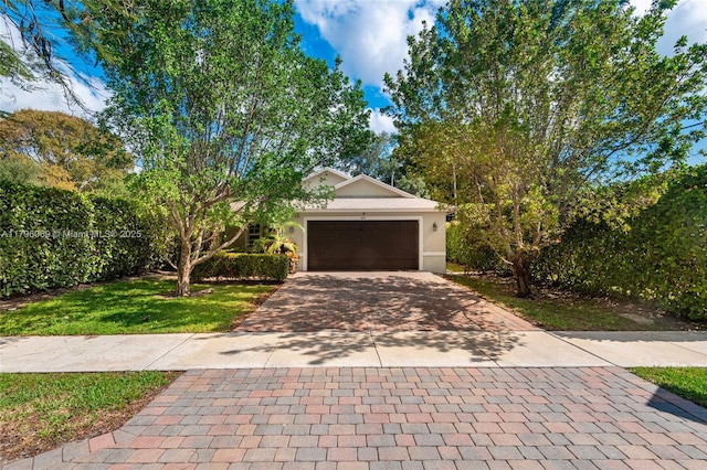 4815 Jefferson Rd, Delray Beach, FL 33445 - view of front of property with decorative driveway, a front lawn, a garage, and stucco siding