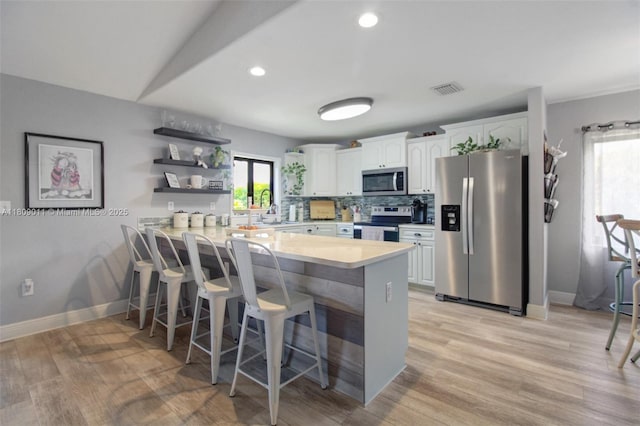 17375 SW 282nd St, Homestead, FL 33030 - kitchen featuring stainless steel appliances, open shelves, a peninsula, light countertops, and white cabinetry