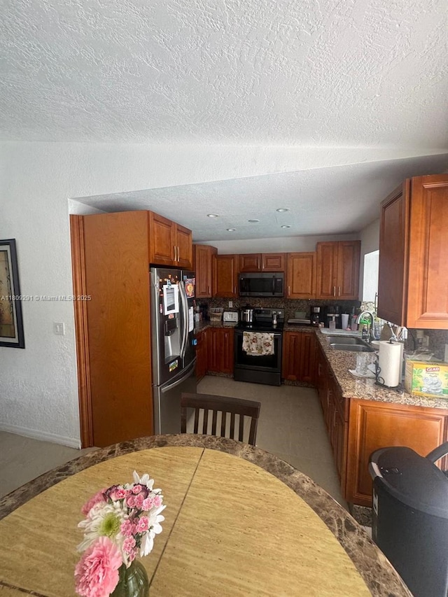 13320 SW 99th St, Miami, FL 33186 - kitchen featuring stainless steel appliances, a sink, brown cabinets, a textured ceiling, and tasteful backsplash
