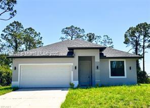 6005 Kumquat Rd, La Belle, FL 33935 - view of front of home with an attached garage, concrete driveway, and stucco siding