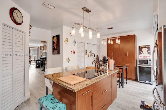 21388 Marina Cove Cir Unit 13-G, Aventura, FL 33180 - kitchen with black electric cooktop, freestanding refrigerator, brown cabinetry, and light wood-style flooring