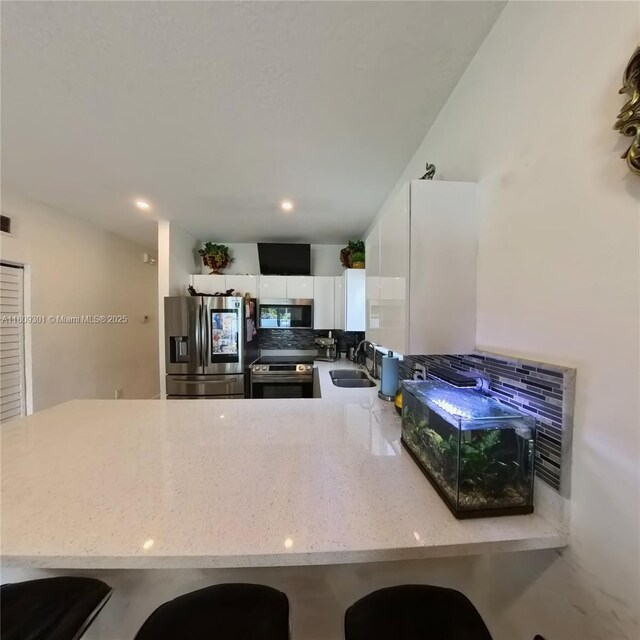 10341 SW 179th St, Miami, FL 33157 - kitchen featuring appliances with stainless steel finishes, backsplash, a sink, white cabinets, and a peninsula