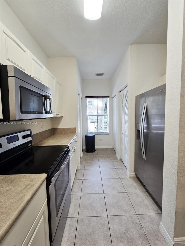 4940 SW 140th Ter Unit 14, Miramar, FL 33027 - kitchen with appliances with stainless steel finishes, white cabinetry, light countertops, light tile patterned flooring, and a textured ceiling