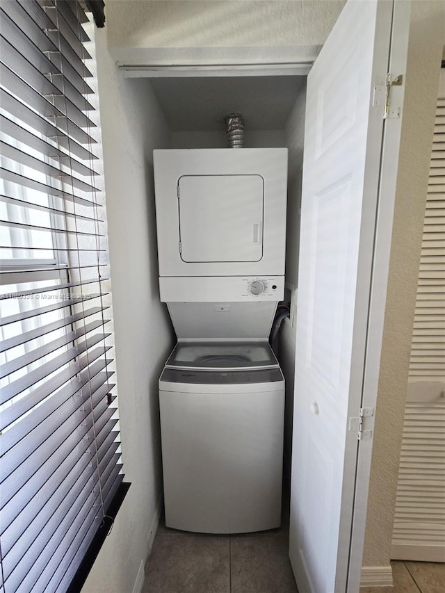 4940 SW 140th Ter Unit 14, Miramar, FL 33027 - laundry area featuring stacked washer and clothes dryer, tile patterned flooring, and baseboards