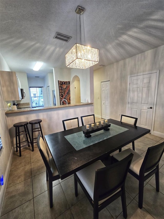 4940 SW 140th Ter Unit 14, Miramar, FL 33027 - tiled dining room with arched walkways, a textured ceiling, a chandelier, and baseboards
