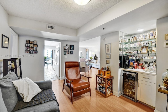1201 S Ocean Dr Unit 609S, Hollywood, FL 33019 - living area with wine cooler, bar, light wood-style floors, a textured ceiling, and baseboards