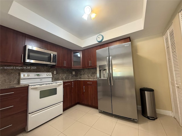 9255 SW 125th Ave Unit 304R, Miami, FL 33186 - kitchen with appliances with stainless steel finishes, a tray ceiling, backsplash, glass insert cabinets, and light tile patterned flooring