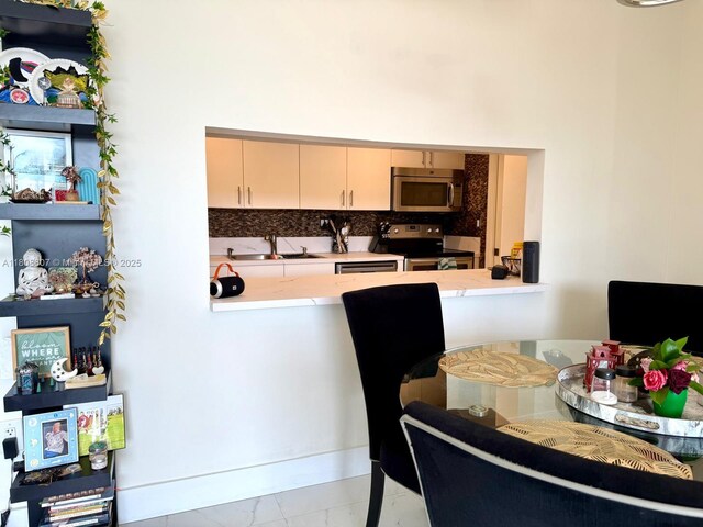 9725 NW 52nd St Unit 421, Doral, FL 33178 - kitchen with stainless steel appliances, a sink, marble look tiles, decorative backsplash, and a towering ceiling
