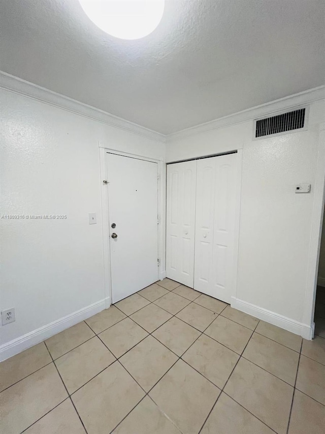 606 W 81st St Unit 224, Hialeah, FL 33014 - unfurnished bedroom featuring crown molding, light tile patterned floors, a closet, baseboards, and a textured ceiling
