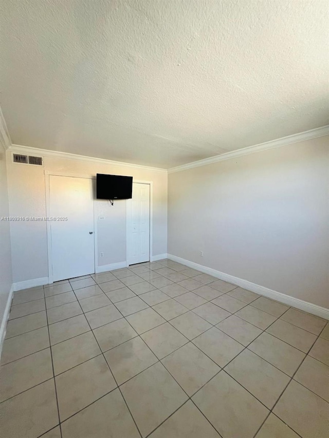 606 W 81st St Unit 224, Hialeah, FL 33014 - unfurnished bedroom featuring ornamental molding, a textured ceiling, baseboards, light tile patterned floors, and a closet