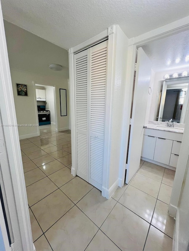 606 W 81st St Unit 224, Hialeah, FL 33014 - hallway with light tile patterned floors, a textured ceiling, baseboards, and a sink