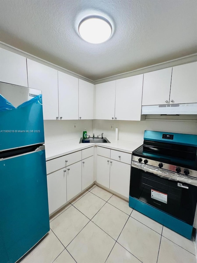 606 W 81st St Unit 224, Hialeah, FL 33014 - kitchen with freestanding refrigerator, stainless steel range with electric cooktop, under cabinet range hood, a textured ceiling, and white cabinetry