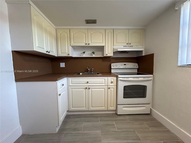 17 NE 2nd Ave Unit 108, Dania Beach, FL 33004 - kitchen featuring white range with electric cooktop, a sink, under cabinet range hood, dark countertops, and baseboards