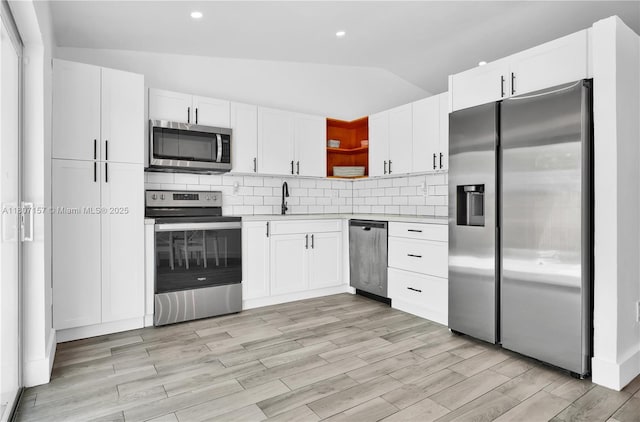 6933 SW 152nd Ct, Miami, FL 33193 - kitchen featuring stainless steel appliances, open shelves, vaulted ceiling, white cabinets, and light countertops