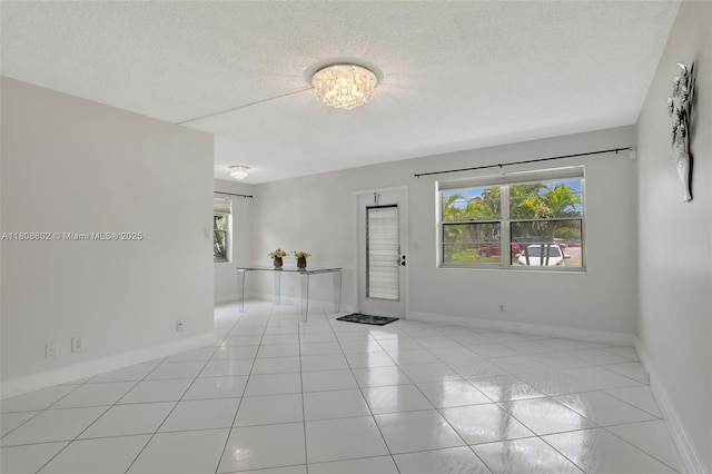 481 Durham Q Unit 481, Deerfield Beach, FL 33442 - empty room featuring plenty of natural light, light tile patterned floors, a textured ceiling, baseboards, and a chandelier