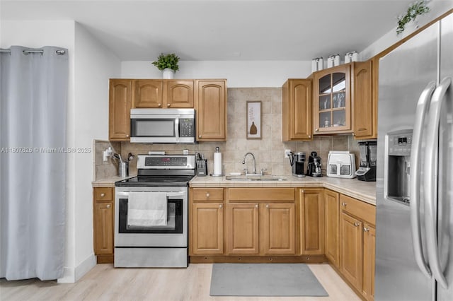 12946 SW 47th Ter, Miami, FL 33175 - kitchen featuring appliances with stainless steel finishes, a sink, light wood-style floors, decorative backsplash, and glass insert cabinets