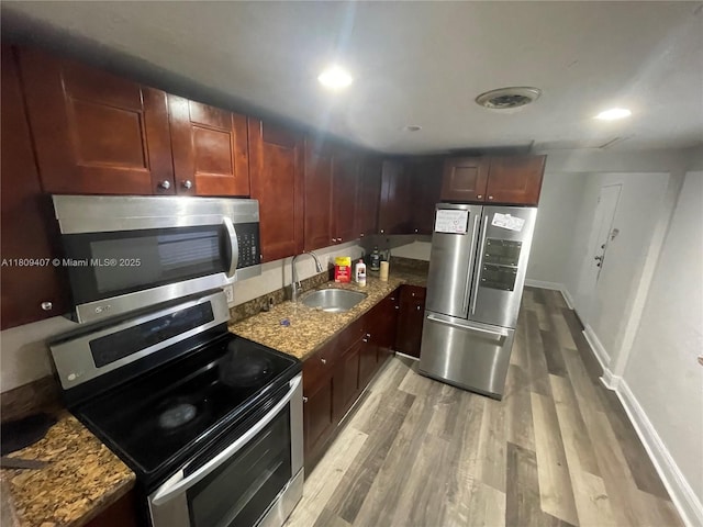 18201 NW 4th Ave, Miami Gardens, FL 33169 - kitchen with appliances with stainless steel finishes, a sink, light wood-type flooring, dark stone countertops, and baseboards