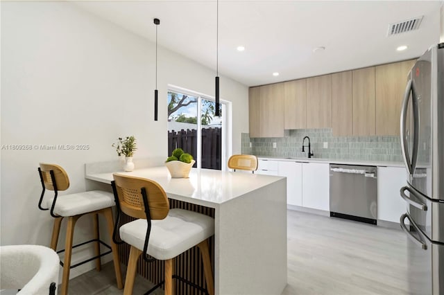 11250 SW 157th Ct, Miami, FL 33196 - kitchen with stainless steel appliances, modern cabinets, a breakfast bar area, tasteful backsplash, and light countertops