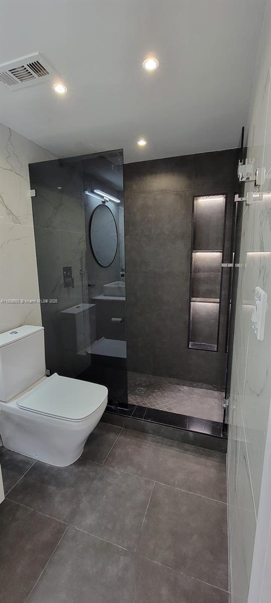 2301 NW 41st Ave Unit 209, Lauderhill, FL 33313 - bathroom with toilet, tiled shower, tile walls, vanity, and recessed lighting