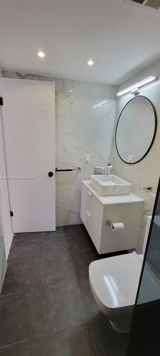 2301 NW 41st Ave Unit 209, Lauderhill, FL 33313 - bathroom featuring vanity, tile walls, toilet, and recessed lighting