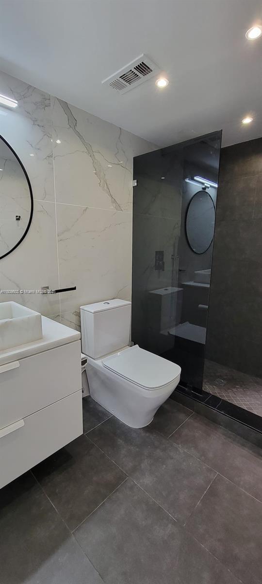 2301 NW 41st Ave Unit 209, Lauderhill, FL 33313 - bathroom with vanity, walk in shower, toilet, tile walls, and recessed lighting