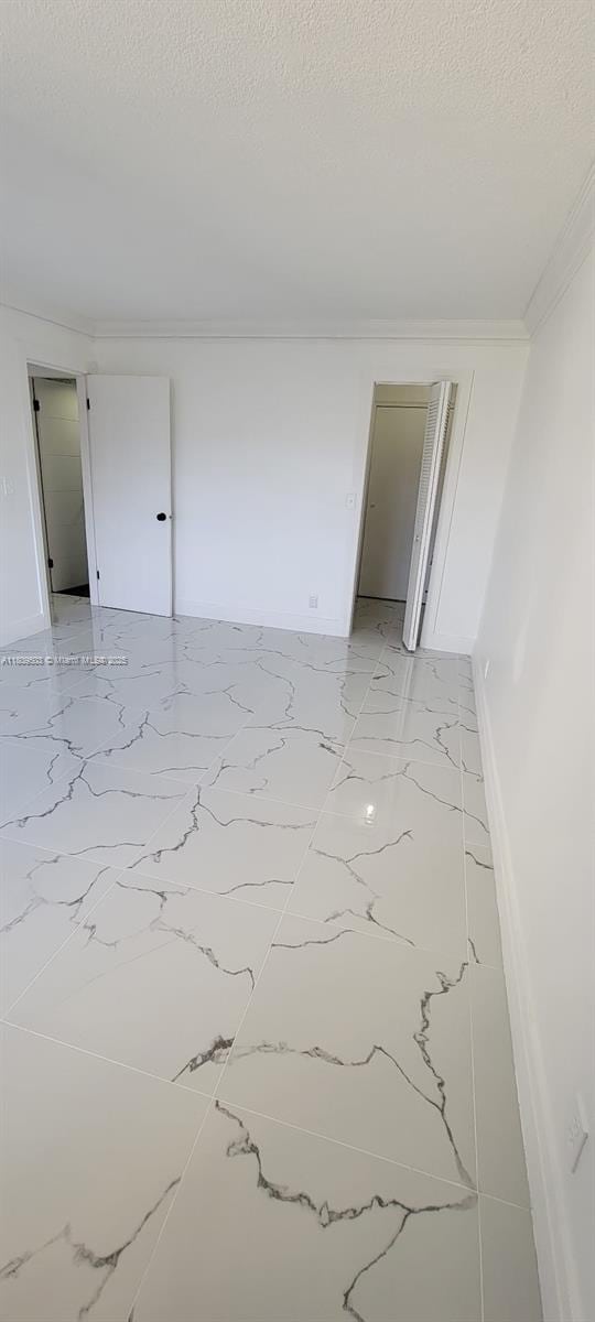 2301 NW 41st Ave Unit 209, Lauderhill, FL 33313 - unfurnished room featuring light marble finish floors, a textured ceiling, crown molding, and baseboards