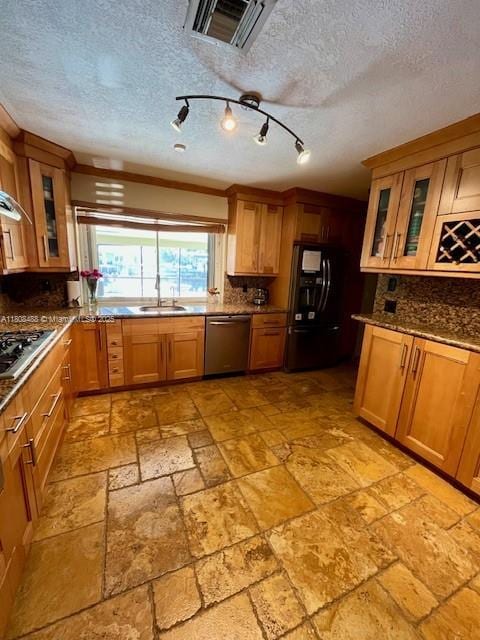 13090 Biscayne Bay Ter, North Miami, FL 33181 - kitchen with stainless steel appliances, a sink, decorative backsplash, brown cabinets, and a textured ceiling