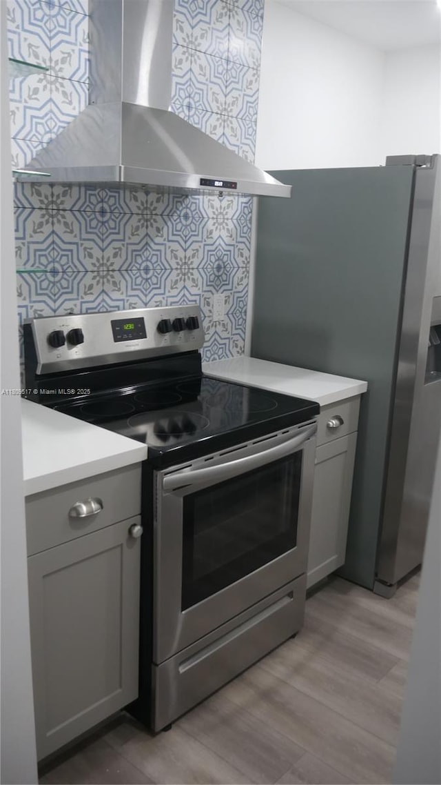 1930 NW 55th St, Miami, FL 33142 - kitchen with stainless steel range with electric stovetop, wall chimney exhaust hood, light wood-type flooring, and light countertops