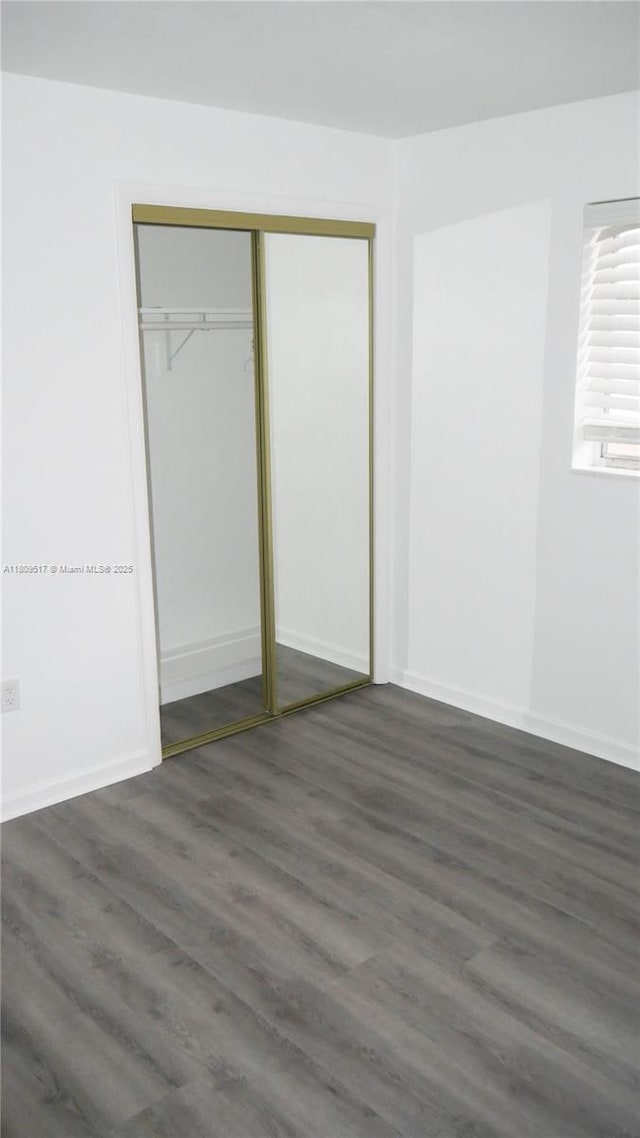 1930 NW 55th St, Miami, FL 33142 - unfurnished bedroom with dark wood-style floors, a closet, and baseboards