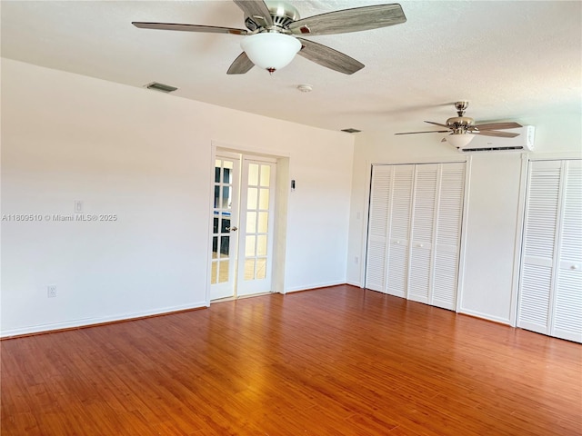 6561 W 13th Ct, Hialeah, FL 33012 - unfurnished bedroom with wood finished floors, two closets, baseboards, and an AC wall unit
