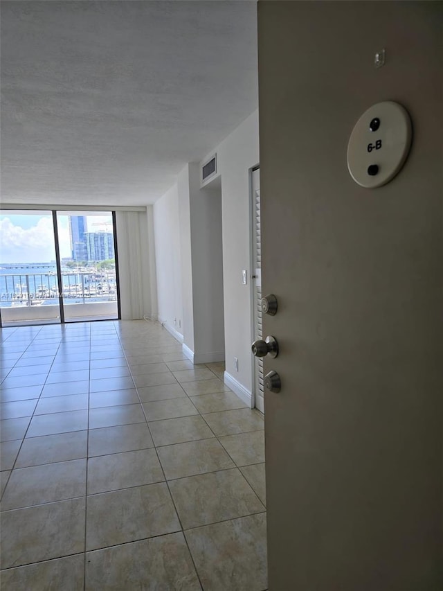 200 SE 15th Rd Unit 6B, Miami, FL 33129 - unfurnished room featuring a wall of windows, baseboards, light tile patterned floors, and a textured ceiling