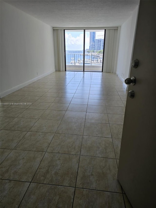 200 SE 15th Rd Unit 6B, Miami, FL 33129 - tiled empty room with floor to ceiling windows, baseboards, and a textured ceiling