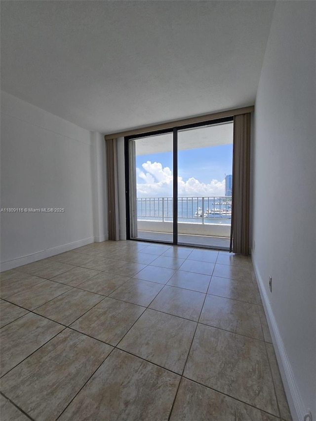 200 SE 15th Rd Unit 6B, Miami, FL 33129 - tiled empty room with expansive windows, a water view, and baseboards