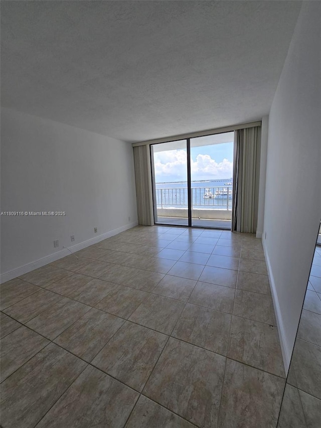 200 SE 15th Rd Unit 6B, Miami, FL 33129 - empty room featuring a wall of windows, light tile patterned floors, and baseboards