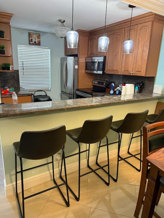 7680 NW 1st St Unit 108, Margate, FL 33063 - kitchen featuring appliances with stainless steel finishes, backsplash, a kitchen bar, decorative light fixtures, and dark stone counters