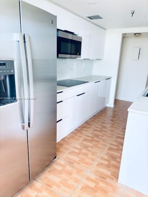 210 174th St Unit 818, Sunny Isles Beach, FL 33160 - kitchen with stainless steel appliances, light countertops, white cabinetry, and decorative backsplash