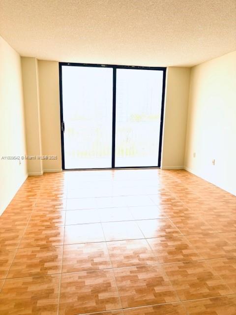 210 174th St Unit 818, Sunny Isles Beach, FL 33160 - unfurnished room with a textured ceiling, a wall of windows, and light tile patterned flooring