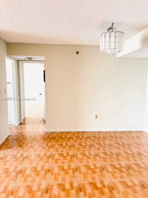 210 174th St Unit 818, Sunny Isles Beach, FL 33160 - empty room with a textured ceiling, a chandelier, baseboards, and light tile patterned flooring