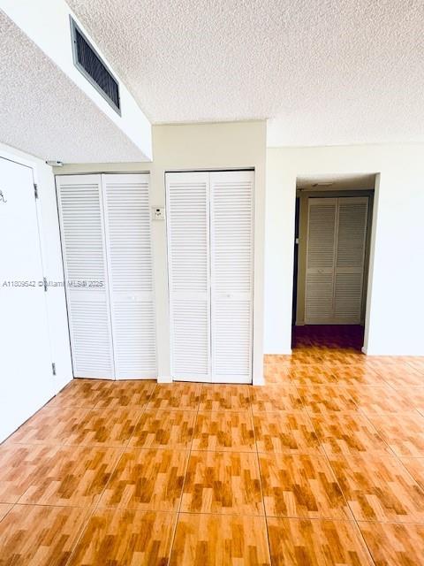 210 174th St Unit 818, Sunny Isles Beach, FL 33160 - unfurnished bedroom featuring a textured ceiling, multiple closets, and wood finished floors