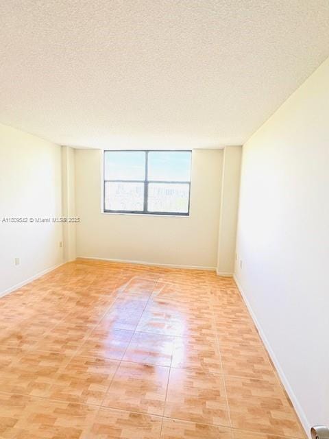 210 174th St Unit 818, Sunny Isles Beach, FL 33160 - empty room featuring a textured ceiling, baseboards, and light wood-style flooring